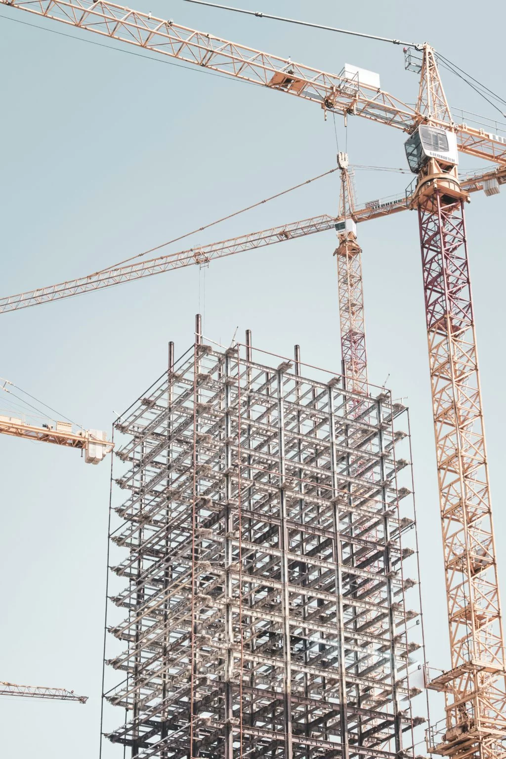Une structure métallique en construction, entourée de plusieurs grues sur un chantier.